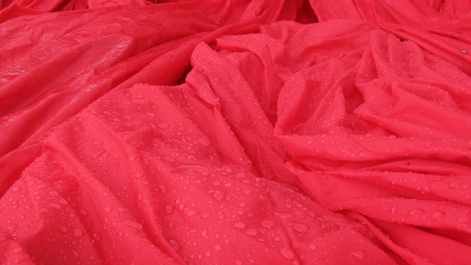Rain coverd red nylon fabric during installation of inflatable sculpture on Governors Island
