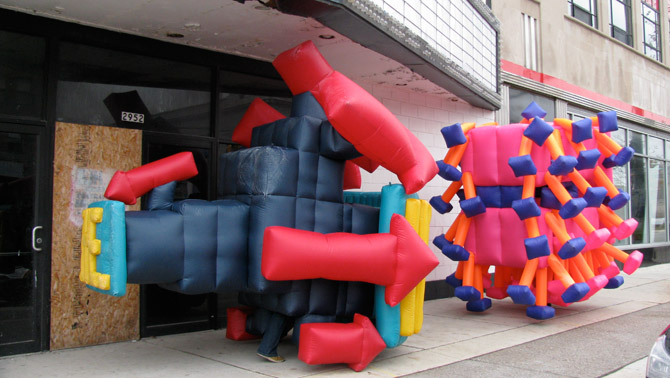 Inflatable Suit Performance Two inflatable suits march down Woodward Avenue in Detroit during a public art performance.