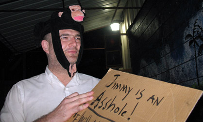 Closup of George Zupp holding a sign wearing a monkey hat.