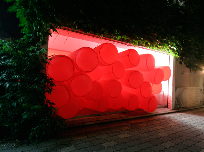 Light illuminates red nylon tubes of an inflatable sculpture